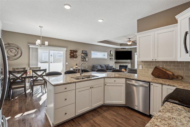 kitchen featuring dark wood finished floors, backsplash, stainless steel dishwasher, white cabinetry, and a sink