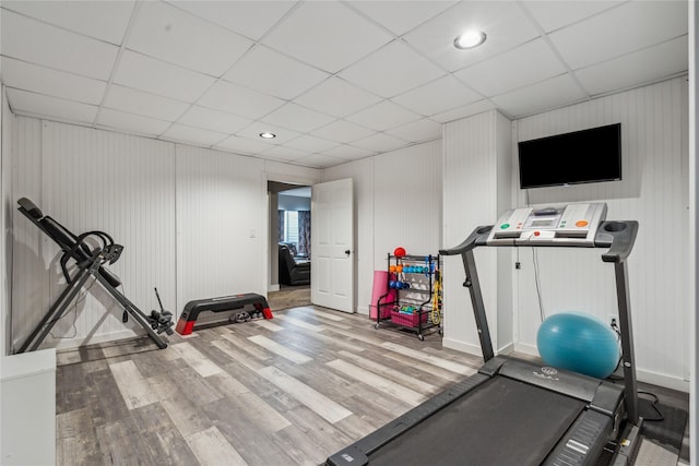 workout area featuring a paneled ceiling, baseboards, and wood finished floors