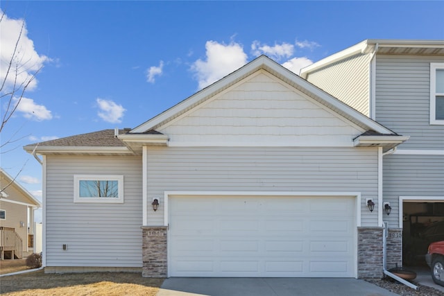 view of front of house featuring stone siding, driveway, and an attached garage