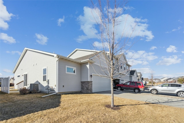 view of side of property with a garage, driveway, a lawn, and a residential view