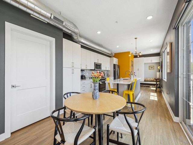 450 SW 7th St Unit 210, Des Moines, IA 50309 - dining area featuring light wood-style flooring, a chandelier, recessed lighting, and baseboards