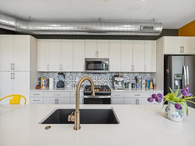 450 SW 7th St Unit 210, Des Moines, IA 50309 - kitchen with stainless steel appliances, a sink, light countertops, and backsplash