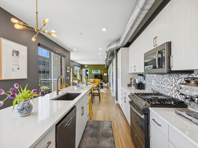 450 SW 7th St Unit 210, Des Moines, IA 50309 - kitchen with appliances with stainless steel finishes, a sink, light wood-type flooring, light countertops, and recessed lighting