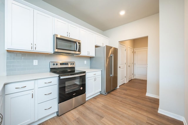 kitchen with light wood finished floors, stainless steel appliances, light countertops, backsplash, and white cabinets