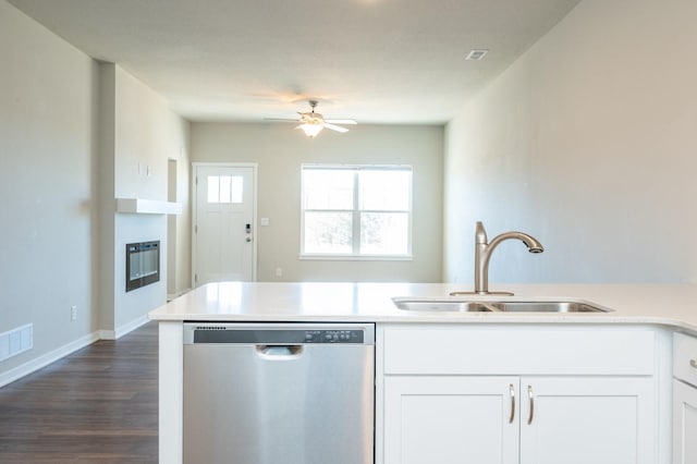 kitchen with white cabinets, a glass covered fireplace, light countertops, stainless steel dishwasher, and a sink