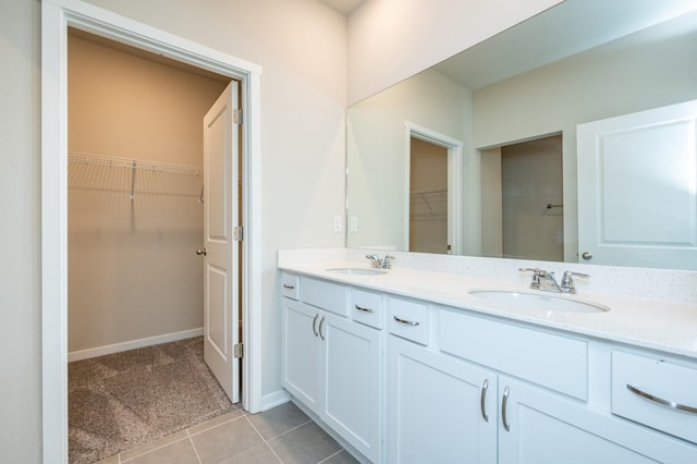 bathroom featuring tile patterned flooring, a walk in closet, a sink, and double vanity