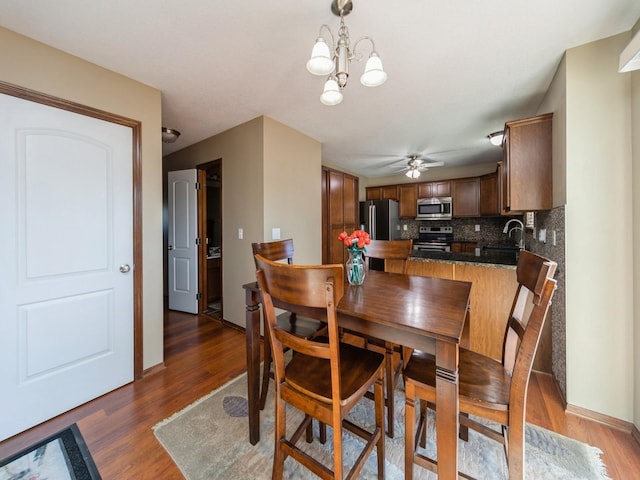 604 NW 8th St, Grimes, IA 50111 - dining room with baseboards, wood finished floors, and ceiling fan with notable chandelier