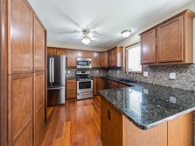 604 NW 8th St, Grimes, IA 50111 - kitchen featuring a peninsula, dark wood-style floors, tasteful backsplash, a sink, and appliances with stainless steel finishes