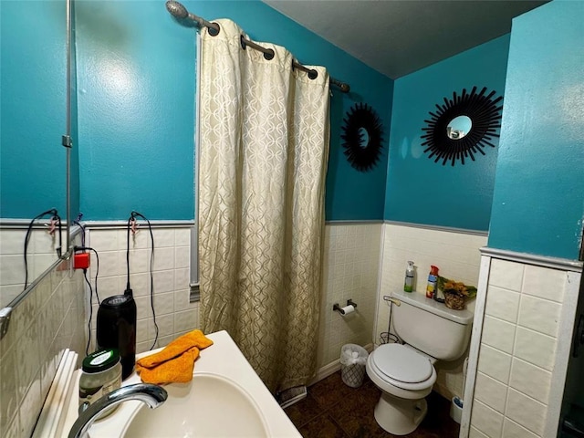 full bath with tile walls, toilet, wainscoting, a sink, and tile patterned flooring