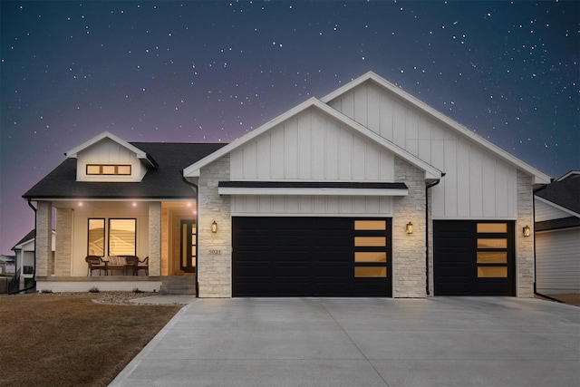 view of front facade with a garage, stone siding, a porch, and board and batten siding