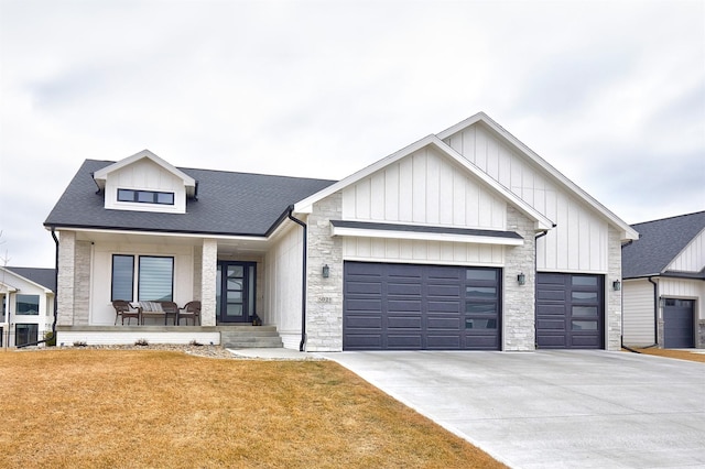 modern farmhouse style home with concrete driveway, an attached garage, covered porch, board and batten siding, and a front yard