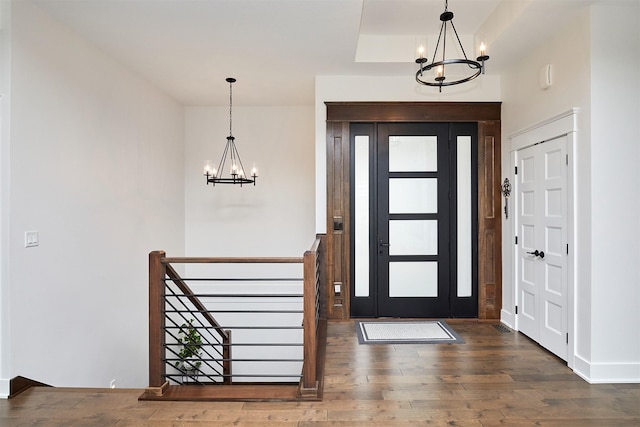 foyer entrance featuring a tray ceiling, wood finished floors, and an inviting chandelier