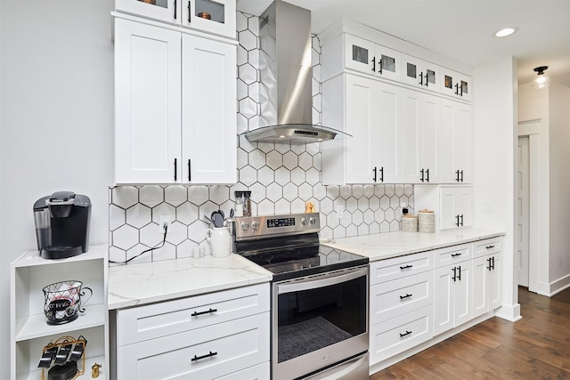 kitchen with light stone counters, dark wood-style flooring, wall chimney exhaust hood, and stainless steel electric stove