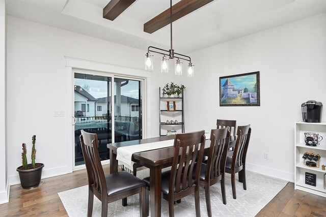 dining area featuring wood-type flooring, beamed ceiling, and baseboards