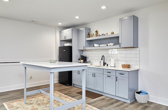 bar featuring tasteful backsplash, baseboards, freestanding refrigerator, light wood-style floors, and a sink