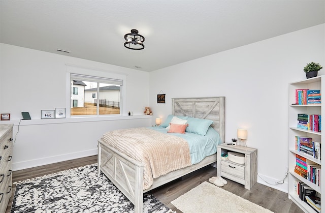 bedroom featuring dark wood finished floors, visible vents, and baseboards