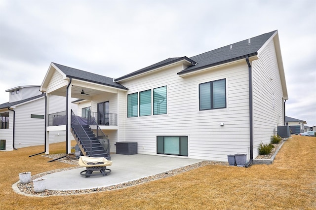 rear view of house with a ceiling fan, a patio, stairway, and a lawn