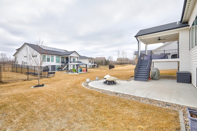 view of yard featuring a ceiling fan, a patio area, fence, a residential view, and stairs