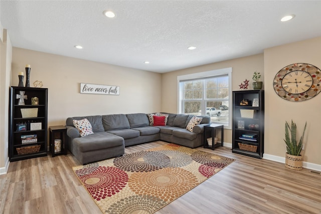 living room featuring a textured ceiling, recessed lighting, light wood-type flooring, and baseboards