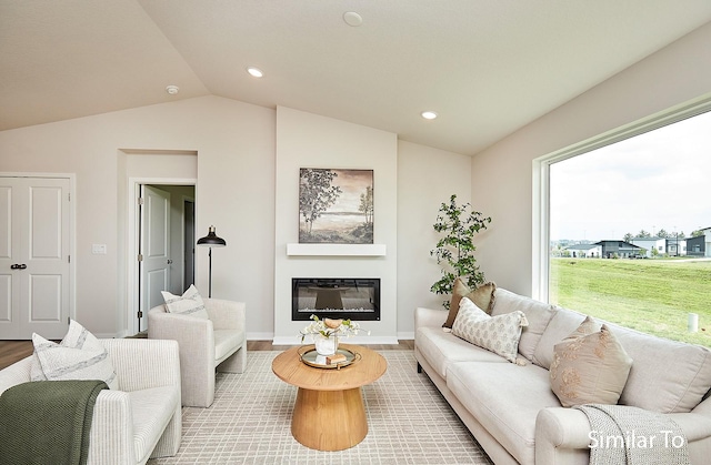 living area with vaulted ceiling, wood finished floors, a glass covered fireplace, and recessed lighting