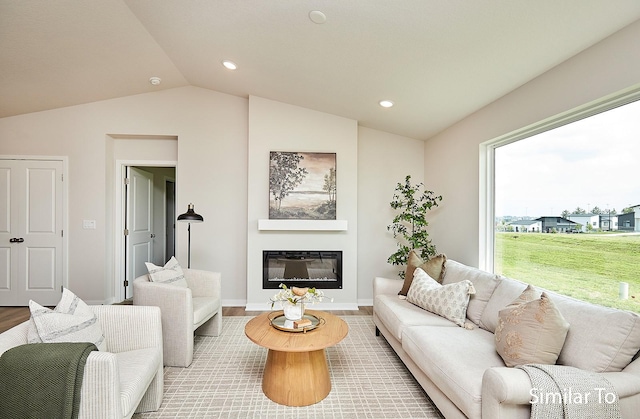 living room featuring wood finished floors, a glass covered fireplace, baseboards, lofted ceiling, and recessed lighting