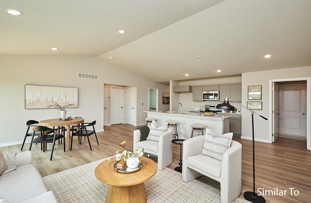 living area with light wood-style flooring, baseboards, lofted ceiling, visible vents, and recessed lighting