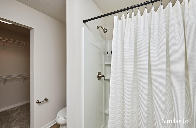 full bathroom with a walk in closet, toilet, baseboards, and a shower with curtain
