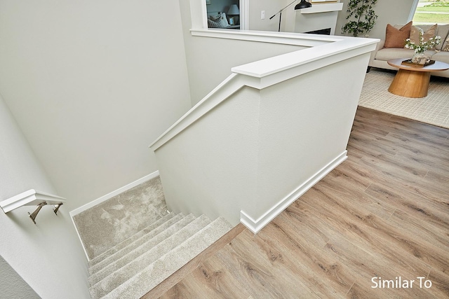 stairs with a fireplace, baseboards, and wood finished floors