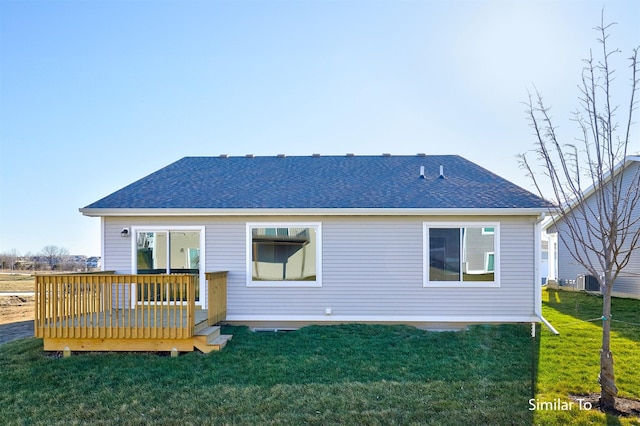 rear view of property featuring roof with shingles, a yard, and a deck