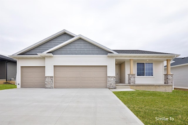 craftsman-style house with concrete driveway, covered porch, stone siding, a front yard, and a garage