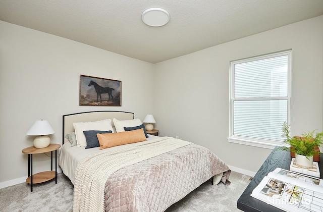 bedroom featuring baseboards, light colored carpet, and a textured ceiling