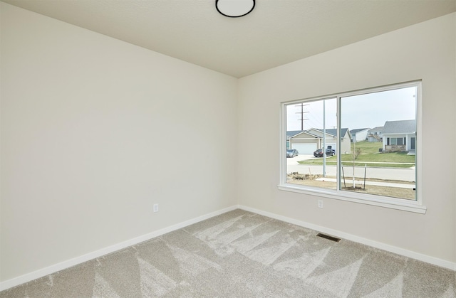 carpeted empty room with visible vents and baseboards