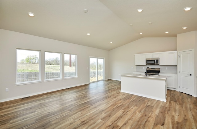 kitchen with vaulted ceiling, open floor plan, stainless steel appliances, and a sink