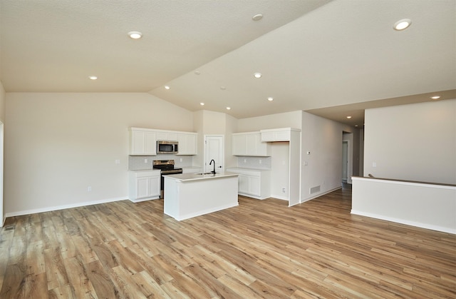 kitchen featuring a sink, open floor plan, decorative backsplash, an island with sink, and appliances with stainless steel finishes