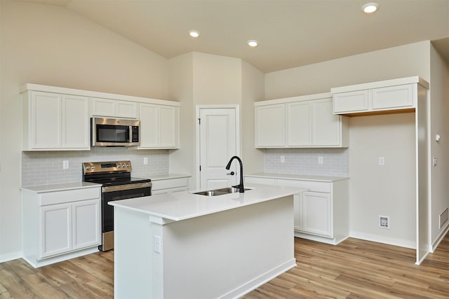 kitchen featuring light wood finished floors, stainless steel appliances, decorative backsplash, and a sink