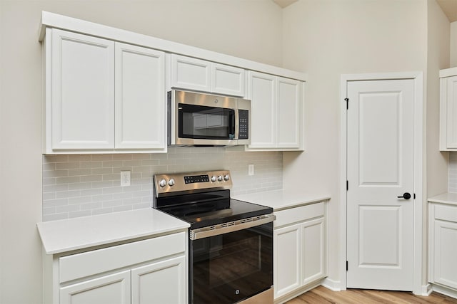 kitchen with stainless steel appliances, decorative backsplash, and white cabinetry