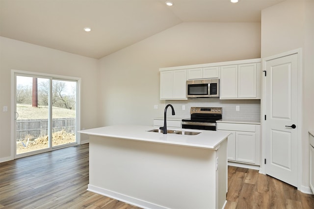 kitchen featuring white cabinets, a sink, vaulted ceiling, decorative backsplash, and appliances with stainless steel finishes