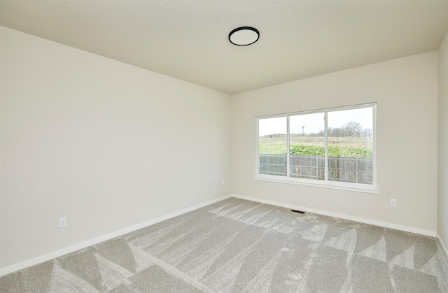 empty room featuring carpet, visible vents, and baseboards