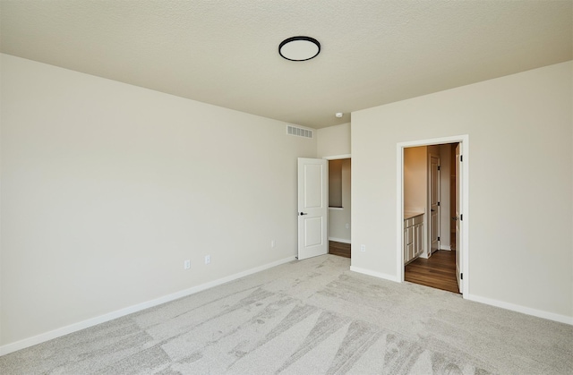 unfurnished bedroom with light carpet, ensuite bathroom, visible vents, and baseboards