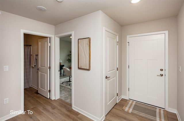 foyer entrance featuring light wood-style flooring and baseboards