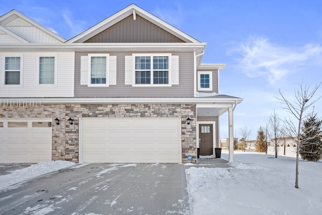 townhome / multi-family property with stone siding, an attached garage, and driveway