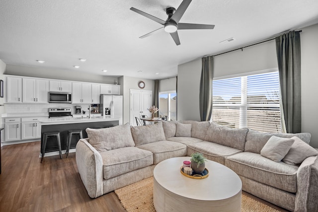 living area with dark wood-style floors, visible vents, a textured ceiling, and ceiling fan