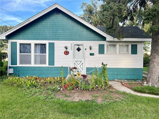 view of front of property with a shingled roof and a front yard