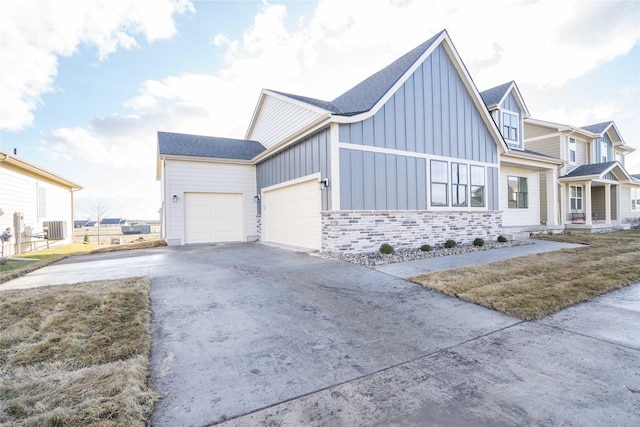 modern inspired farmhouse featuring roof with shingles, an attached garage, board and batten siding, stone siding, and driveway