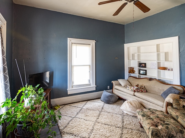 living room with a ceiling fan and baseboards