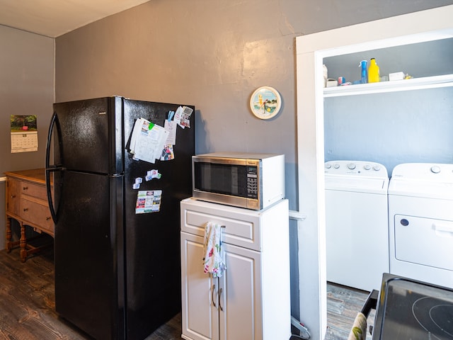 kitchen featuring dark wood-style flooring, stainless steel microwave, freestanding refrigerator, and washer and dryer