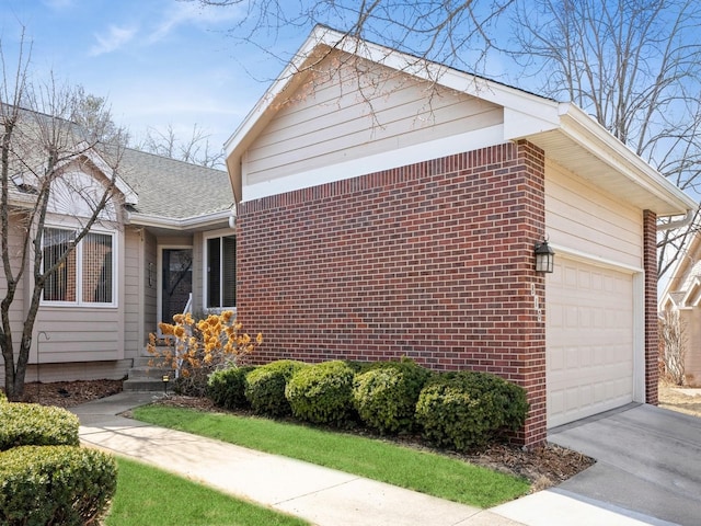 view of property exterior featuring driveway, a garage, and brick siding