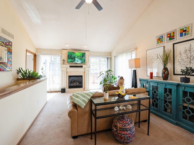 living room featuring lofted ceiling, visible vents, a glass covered fireplace, light carpet, and a textured ceiling