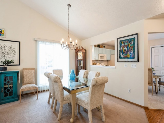 dining space with light carpet, an inviting chandelier, baseboards, and vaulted ceiling