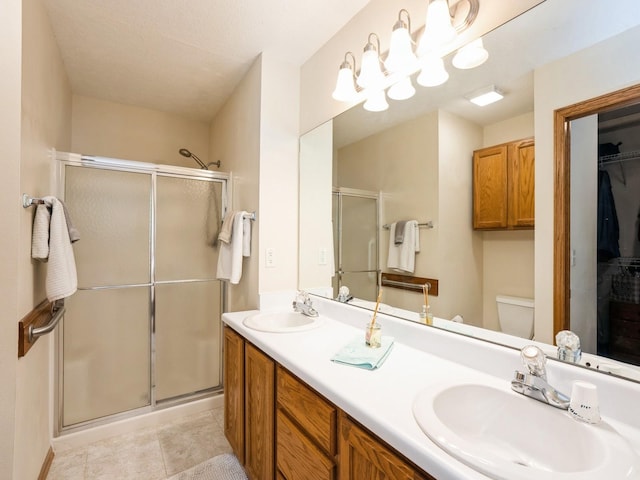 full bathroom featuring double vanity, a shower stall, a sink, and tile patterned floors